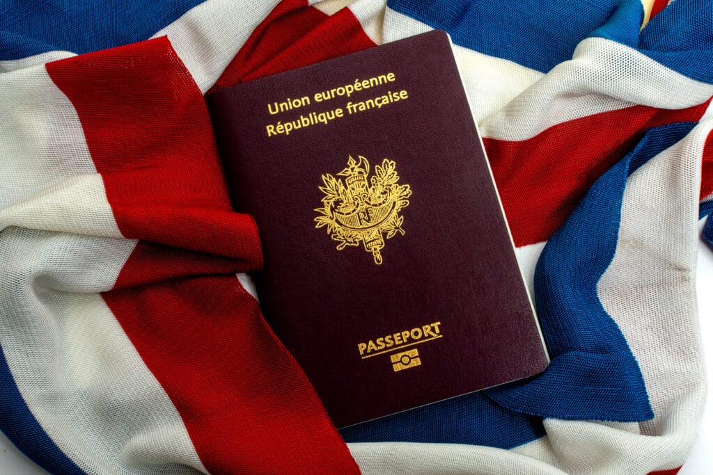 Passeport bordeaux français (Union européenne, République française, PASSEPORT) posé sur un tissu aux couleurs du drapeau tricolore.